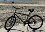29" Black Rock 7sp matte Black bicycle on a sandy beach